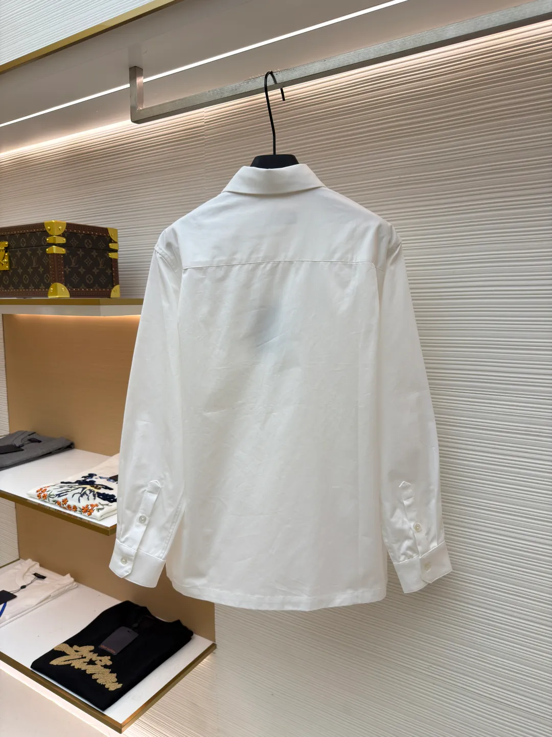 LOUIS VUITTON Embossed Pocket Lapel Shirt ●Original version: Purchased and developed for 3989 ●Item number: 1681491-B05 ●Fabric: Cotton twill woven fabric ●Technology: Concave embossed printing ●Color: white ●Version: Fitted version ●Weight: about 370 grams ●Size: XS-S-M-L ●Description: The twill pattern is obvious on the front of the fabric and blurry on the reverse. Single yarn is used in both warp and weft directions, and the linear density is close. The warp density of the fabric is slightly higher than the weft density, and the hand feel is relatively soft. The fabric has excellent stability, is not easy to deform, and prevents bulging; cotton fiber has good hygroscopicity, which keeps the fabric in a water balance, making people feel comfortable, and adding to the sophistication of the fabric. The concave and convex embossing process is formed by heating and shaping the upper and lower dies. The rollers press the fabric at a certain temperature, and the three-dimensional hierarchical convex surface is produced through mechanical embossing. The fabric produces a concave and convex pattern with a relief-style three-dimensional effect and a special gloss effect. The three-dimensional shape, pattern and text have a strong three-dimensional sense, adding a decorative art effect, clear layers, concentrated three-dimensional image, and accurate perspective angle. The collar can be adjusted with buttons for both formality and comfort; the pleats and tabs at the back are classic shirting techniques, with the pleats providing extra room for movement and the tabs keeping the shirt in shape when hanging. The button front uses custom-fit buttons that are positioned accordingly, and together these details ensure the shirt's functionality and crisp look. The overall wiring is straight and delicate, the fabric is comfortable and soft, and the color is consistent without color difference. It can be matched with the same style to create a fashionable look and control various occasions. Customized accessories, complete with three standards, same style for men and women!